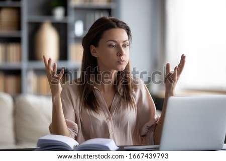 Unhappy young woman looking at laptop screen, irritated by bad gadget work, low internet connection, working remotely at home. Stressed attractive lady annoyed by hard work task or system crash. Royalty-Free Stock Photo #1667439793