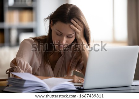 Head shot exhausted female student holding head in hand, tired of monotonous study alone at home. Sleepy unhappy young woman feeling lack of energy motivation, working distantly online on computer. Royalty-Free Stock Photo #1667439811