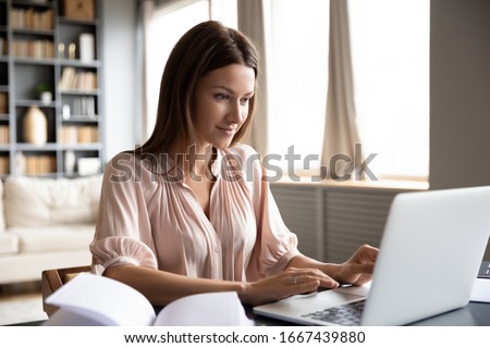 Head shot pleasant happy young woman freelancer working on computer at home. Attractive businesswoman studying online, using laptop software, web surfing information or shopping in internet store. Royalty-Free Stock Photo #1667439880