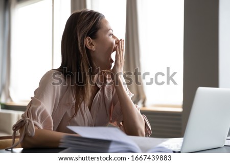 Head shot distracted from work study young woman yawning, having lack of energy during workday at home or office. Tired businesswoman feeling bored, looking at window, chronic fatigue concept. Royalty-Free Stock Photo #1667439883