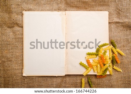 Italian fusilli or rotini and open recipe book with blank page, top view