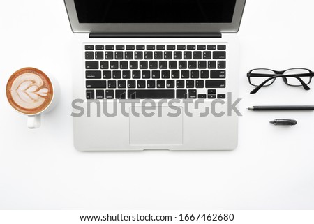 Top view of white office desk table with laptop computer, cup of coffee and supplies. Top view with copy space, flat lay.