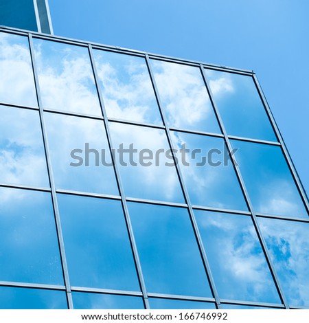 Sky and clouds reflected in windows of modern office building.