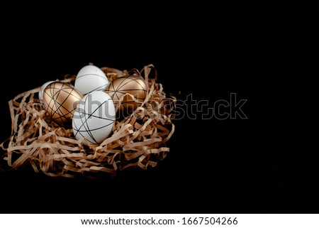 Easter goldenand white decorated eggs in nest on black background . Minimal easter concept copy space for text. Top horizontal view