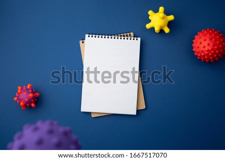 Spiral notebook with virus abstract strain model on blue background close up flat lay. Pandemic protection concept against coronavirus top view.