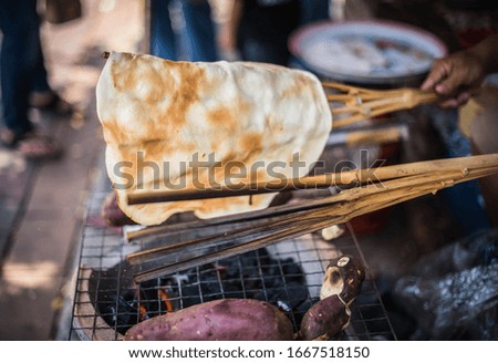 Glutinous rice, grinded into sheets, grilled over the fire as a snack for Thai people