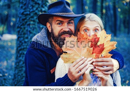 Autumn couple on fall nature background. Carefree young woman with handsome bearded man in trendy vintage pullover or sweater and cowboy hat