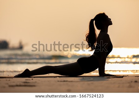 Silhouette of Athletic Asian young woman practice Cobra Pose on the sand and beach with sunset beautiful sea in Tropical island,Feeling comfortable and relax in holiday,Vacations Yoga Concept Royalty-Free Stock Photo #1667524123