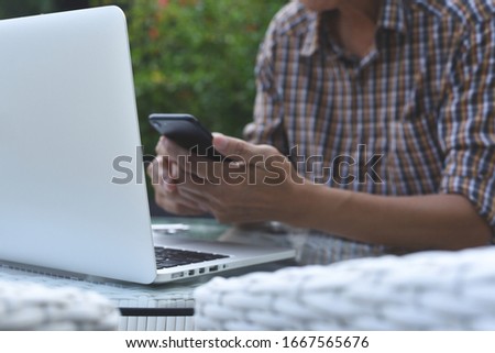 Online working, portable office, E-learning, browsing internet, people lifestyle concept. Casual business man, looking at mobile smart phone, working on laptop computer, close up