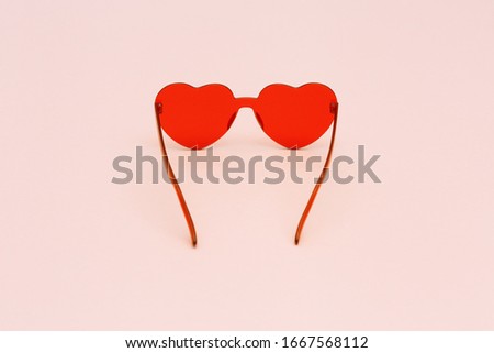 Stylish heart shaped glasses on pink background with copy space. Beautiful trendy red sunglasses. Fashion summer concept. 