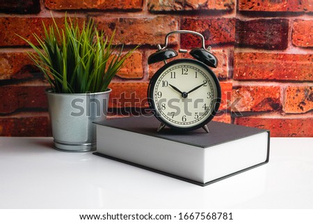 Alarm Clock and book on brick background. Business, motivation, quotes and Copy space 