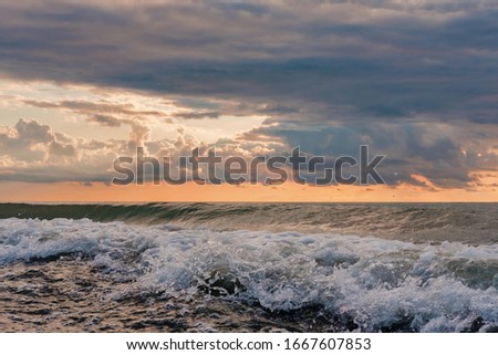 Detail of stormy sea waves with dramatic cloudy sunset sky background