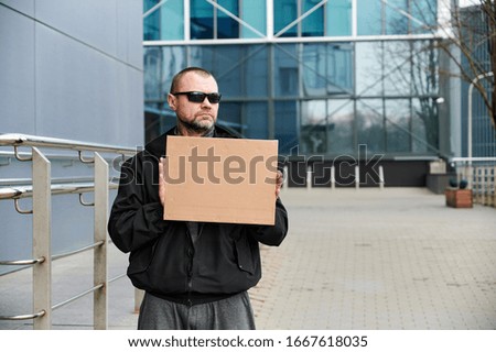 Street photo of an adult Caucasian man with a banner in his hands in a black jacket in the afternoon