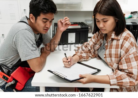 Young asian thai couple listing to do list they have to do. New year resolution. Woman writing something on a paper while her boyfriend giving opinion or arguing.