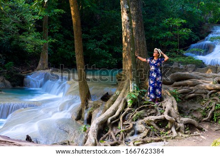 Woman stand look waterfall  at Erawan Waterfall and  natural in Kanchanaburi province Thailand.
Erawan Waterfall  Is a beautiful and famous water fall.