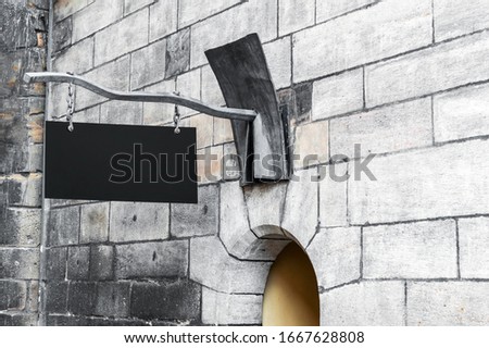 Blank metal signboard above arch on old stone wall.