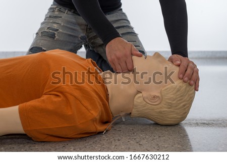 Man teaching cardiopulmonary resuscitation with a dummy on a white background. Front-chin manoeuvre (Photo 3 of 18).