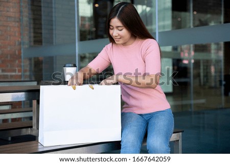Young pretty woman with blank screen on white paper shopping bag mock up with clipping path,  Empty space on shopping bag for design insert logo or graphic for advertising, copy space