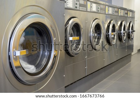 Washing machines lined up in a laundromat Royalty-Free Stock Photo #1667673766