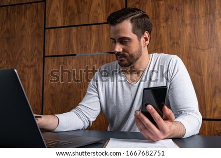A handsome man in office typing the contract on laptop. The concept of searching internet. Casual wearing.