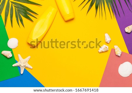 Yellow bottles of sunscreen cream, tropical palm leaves, shells, starfish on colorful background top view flat lay copy space. Sun protection Summer background vacation travel concept Summer cosmetics