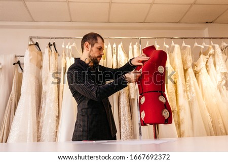 Male tailor or seamstress taking mannequin measurements for cloth pattern with measuring tape in fashion design studio, woman designer working with dummy in workshop, dressmaking and sewing concept