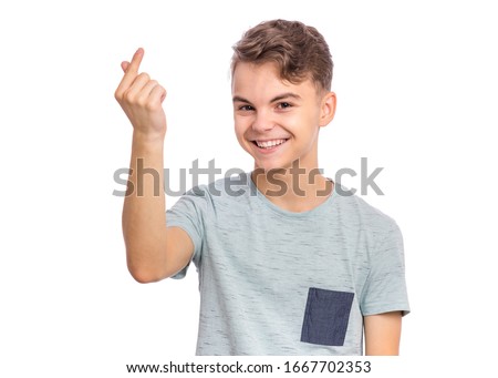 Portrait of handsome young teen boy showing sign symbol of money by fingers, isolated on white background. Smiling child doing rich gesture. Teenager making cash sign gesture rubbing fingers together.