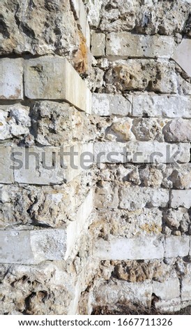 View of the old wall of large gray stone. Ancient stone background with free space for text or image. Corner, ledge of the masonry wall. Perspective view of the stone fence.                          