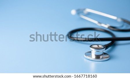 Black stethoscope for doctor diagnostic coronavirus disease, medical tool for health on blue background with copy space Royalty-Free Stock Photo #1667718160