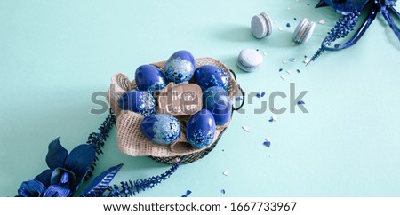 Creative Easter layout made of colorful eggs and flowers on blue background. Circle wreath flat lay concept. The concept of the Easter holidays.