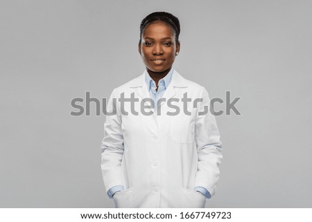 medicine, profession and healthcare concept - smiling african american female doctor or scientist in white coat over grey background Royalty-Free Stock Photo #1667749723