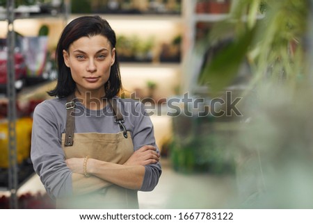 Waist up portrait of successful female business owner posing confidently in flower shop, copy space