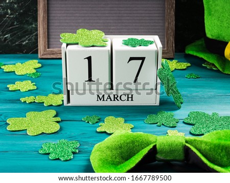 St Patricks Day date 17 march on wooden calendar on dark green wooden rustic background with shamrocks and leprechaun costume accessories