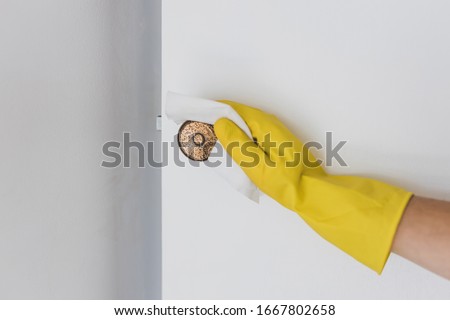 concept of disinfecting surfaces from bacteria or viruses sill-life, hand with glove cleaning door knob with disinfectant wet wipe  Royalty-Free Stock Photo #1667802658