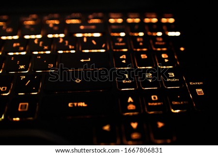 Computer keyboard with Russian and English layout. Backlit by neon light.