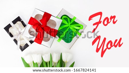 For You text message sign on light background. White tulip flowers and paper gift boxes with colorful ribbon bows flat lay. Flower Bouquet congratulations greeting card. Website banner top view