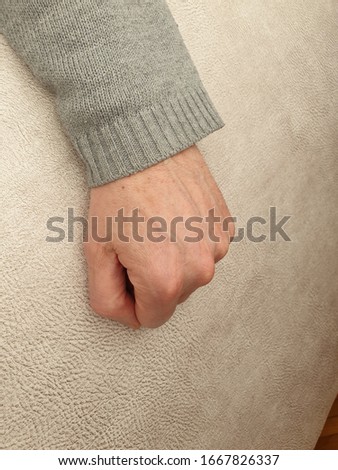 Man's hand with clenched fist. Reclined on side.
