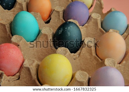 Many colored, colored eggs lie on a pink background, Easter holiday.