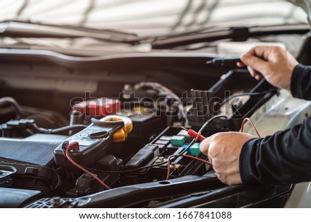 Professional mechanic man holding multimeter tool for testing and troubleshooting failure of a car