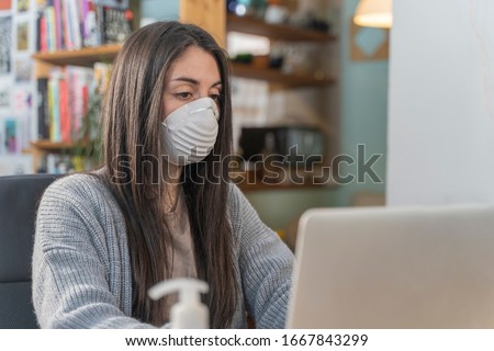 Coronavirus. Young business woman working from home wearing protective mask. Business woman in quarantine for coronavirus wearing protective mask. Working from home with sanitizer gel.  Royalty-Free Stock Photo #1667843299