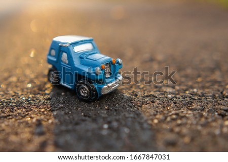 Travel concept image. Miniature car up closed shot over nice blurred sunset scenery background