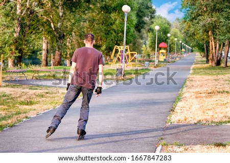 Sporting, athletic boy rollerscating in park alley on summer day.