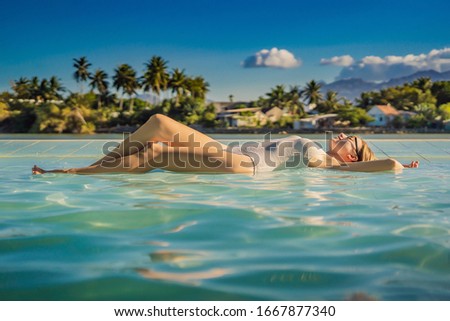 Luxury resort swimming pool. Beautiful woman tourist relaxing in holiday retreat on summer travel vacation. Bikini girl in sunbathing swimsuit enjoying ocean background
