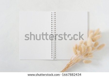 Blank white spiral notebook with  natural dried hare's tail grass bouquet on white background. Top view image. Feminine styled stock photography for blog posts and social media content.