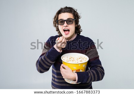 Man wearing a pair of 3D glasses and eating popcorn isolated on white background
