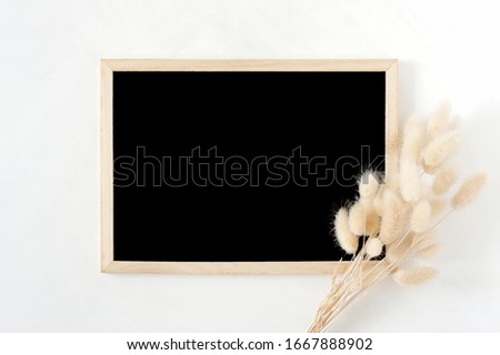 Blank wooden chalk board with natural dried hare's tail grass bouquet on white background. Top view image. Feminine styled stock photography for blog posts and social media content.