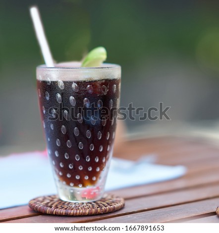 Cold tea or coffee In tall glass on table with lemonade