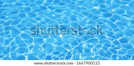 Water background, ripple and flow with waves. Summer blue swiming pool pattern. Sea, ocean surface. Overhead top view with place for text. Panoramic banner. Royalty-Free Stock Photo #1667900125