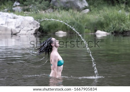 Girl throwing water head swimming in a mountain river