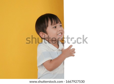 Portrait of  asian boy looking at the white board with copy space isolated over yellow background. Concept for website and promotion banners.